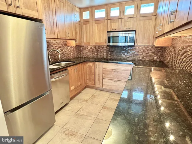 a kitchen with granite countertop a refrigerator and a sink