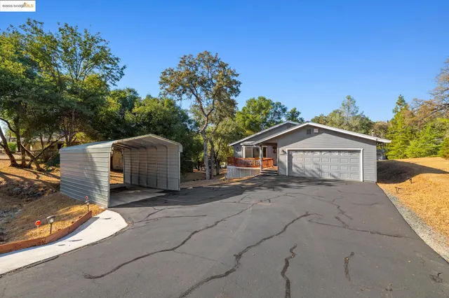 a view of a house with a yard and large tree