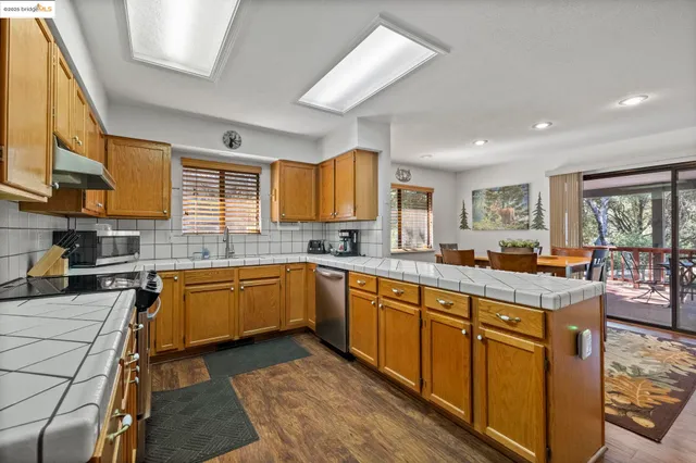 a open kitchen with stainless steel appliances granite countertop a stove top oven a sink dishwasher and cabinets with wooden floor