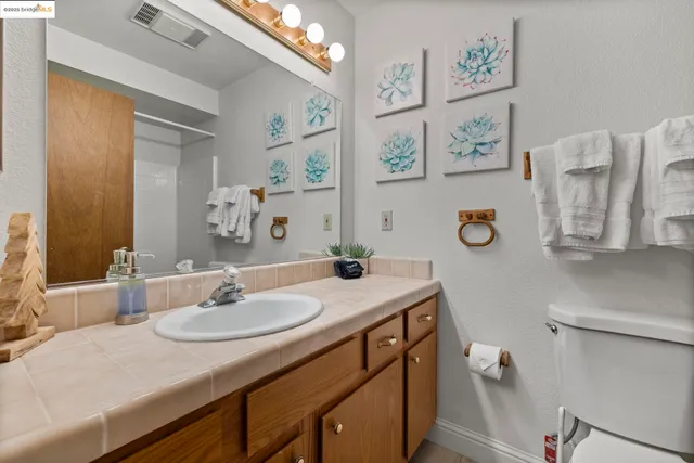 a bathroom with a granite countertop sink vanity mirror and toilet