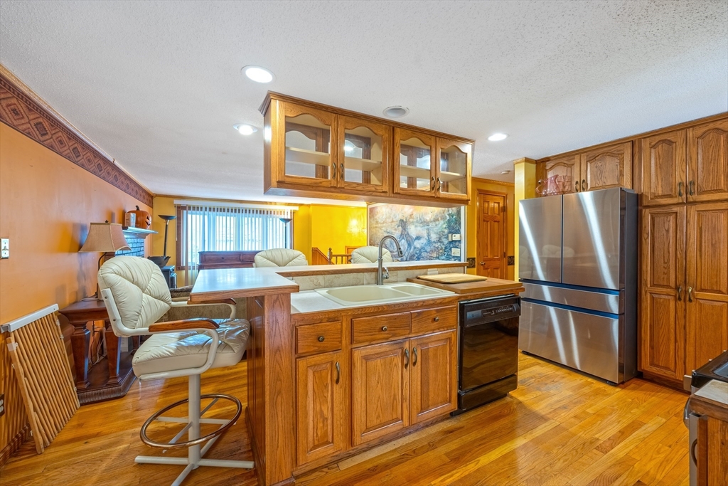 60 Elizabeth Street Feeding Hills, MA 01030 - Photo 4 of 39 a kitchen with granite countertop stainless steel appliances a refrigerator a stove a sink dishwasher and wooden cabinets with wooden floor