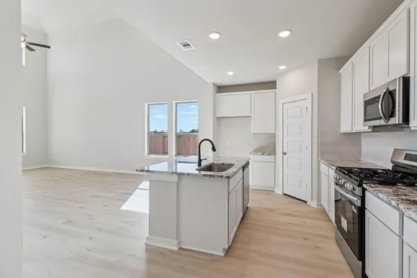 a kitchen with stainless steel appliances granite countertop a sink stove and cabinets