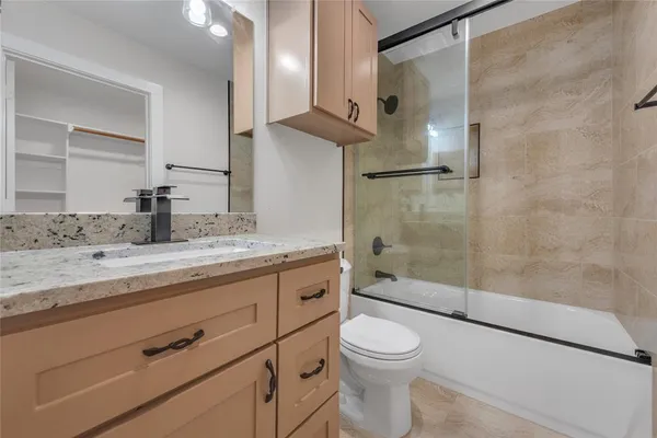 a bathroom with a granite countertop sink a toilet and shower