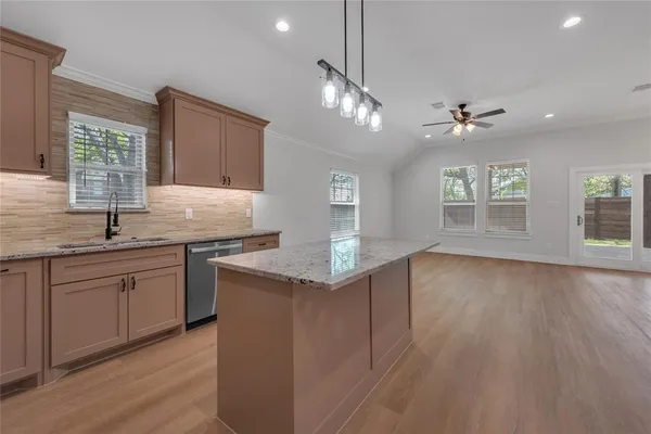 a kitchen with granite countertop a sink cabinets and wooden floor