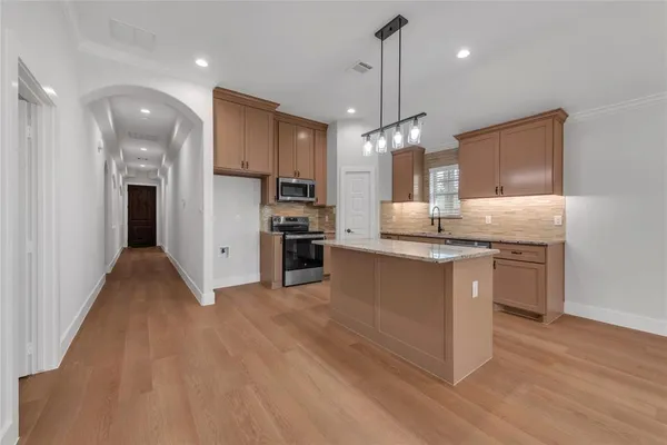 a kitchen with kitchen island granite countertop a stove a sink a refrigerator and a wooden floor