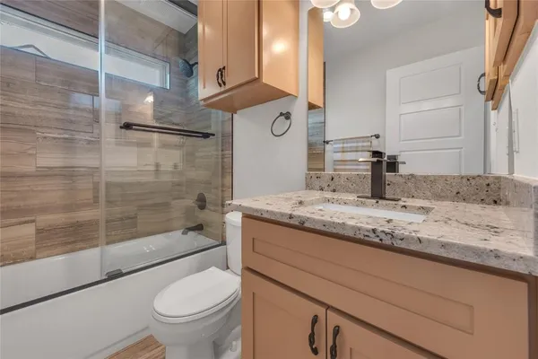 a bathroom with a granite countertop sink toilet and shower