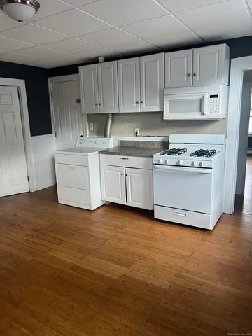 a kitchen with granite countertop a sink a stove a refrigerator and white cabinets