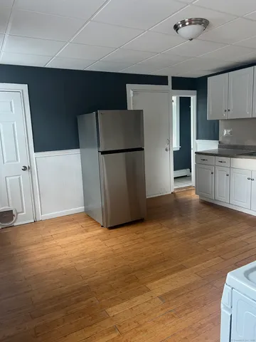 a view of kitchen with refrigerator cabinets and wooden floor