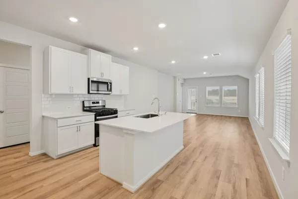 a kitchen with white cabinets a sink stove and wooden floor