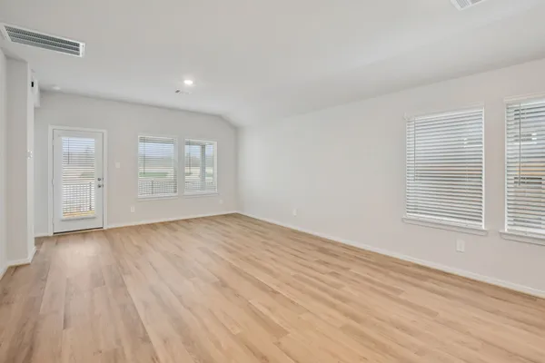 an empty room with wooden floor and windows