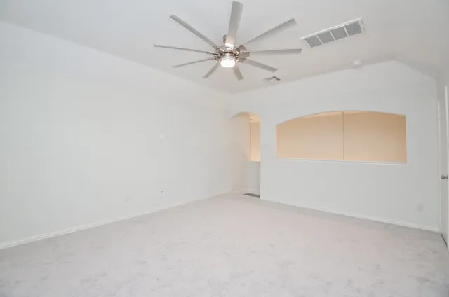 an empty room with a window and a ceiling fan