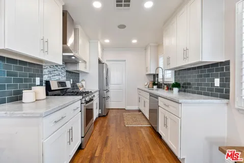a kitchen with granite countertop a sink a counter top space stainless steel appliances and cabinets