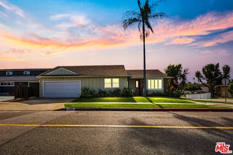 a front view of a house with a yard and palm trees