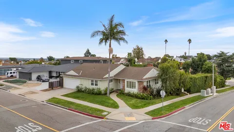 a front view of a house with a yard and palm trees