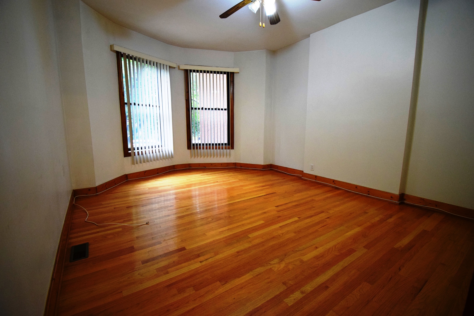 4326 North Kenmore Avenue, Unit 1 Chicago, IL 60613 - Photo 2 of 14 an empty room with wooden floor chandelier fan and windows