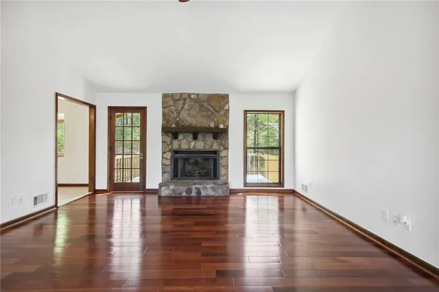 a view of an empty room with window and wooden floor