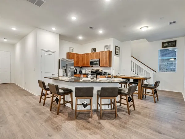 a kitchen with sink a stove and chairs with wooden floor