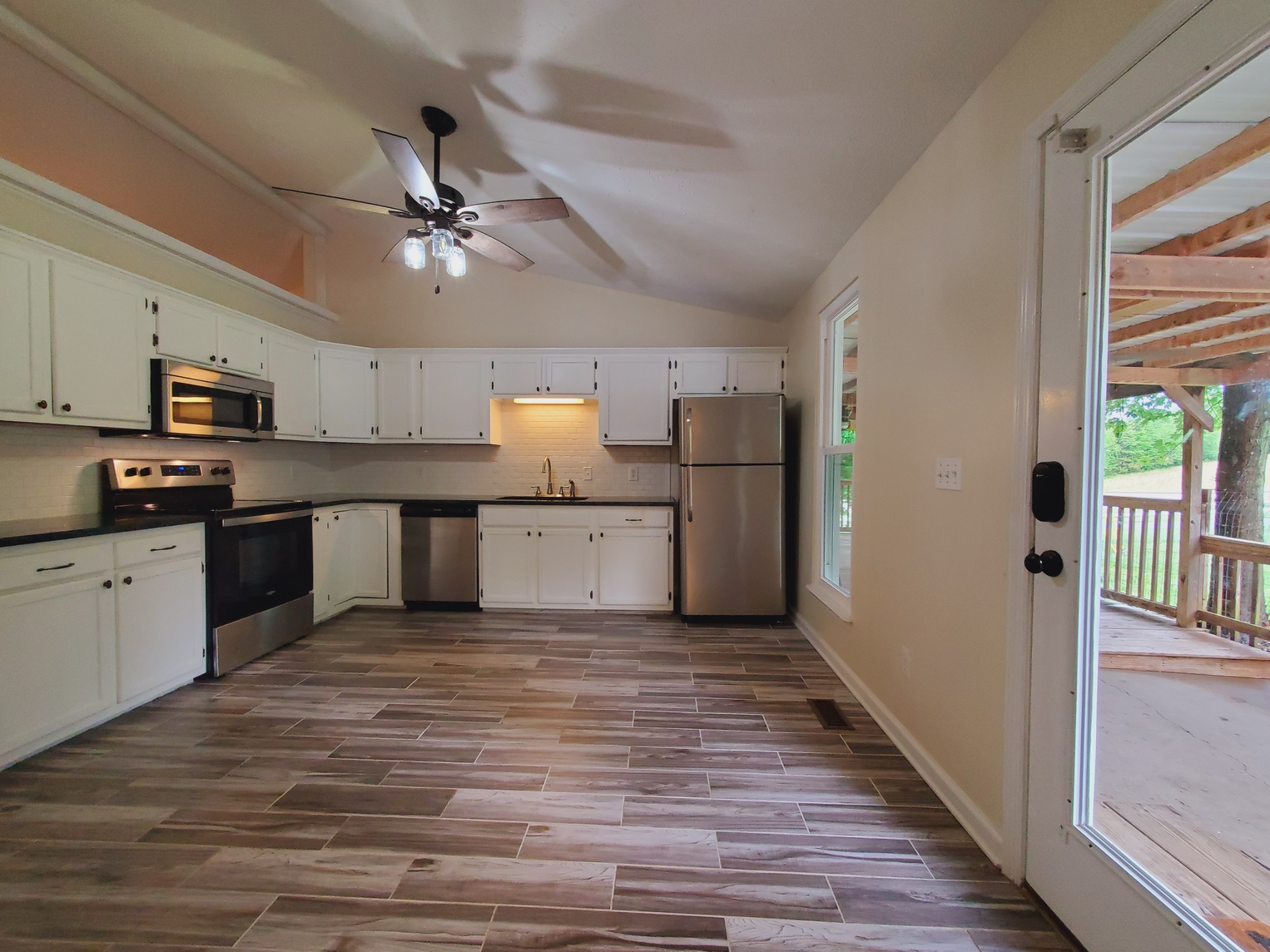 324 West Harper Road Portland, TN 37148 - Photo 6 of 25 a kitchen with granite countertop a refrigerator oven a sink dishwasher and white cabinets with wooden floor