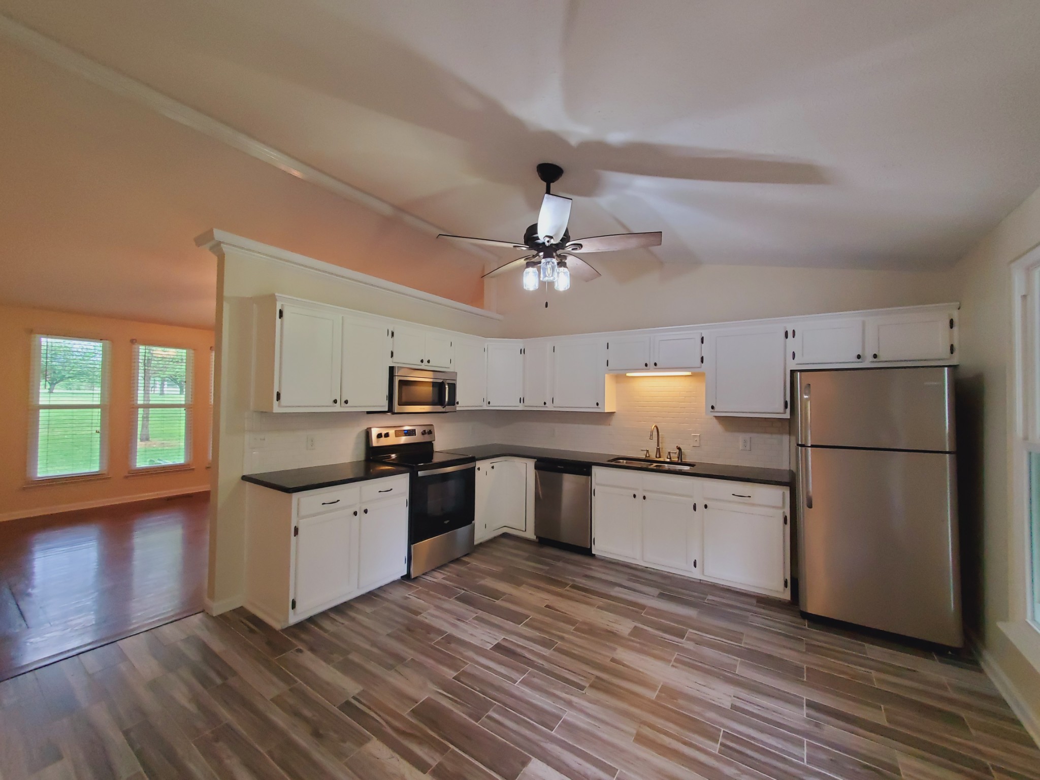 324 West Harper Road Portland, TN 37148 - Photo 7 of 25 a kitchen with granite countertop a refrigerator oven a sink dishwasher and white cabinets with wooden floor