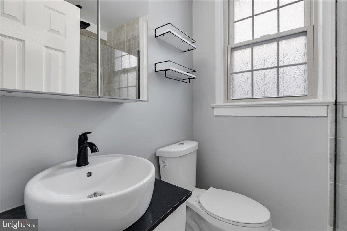 1301 Longfellow Street Northwest, Unit 207 Washington, DC 20011 - Photo 15 of 25 a bathroom with a toilet a sink and mirror