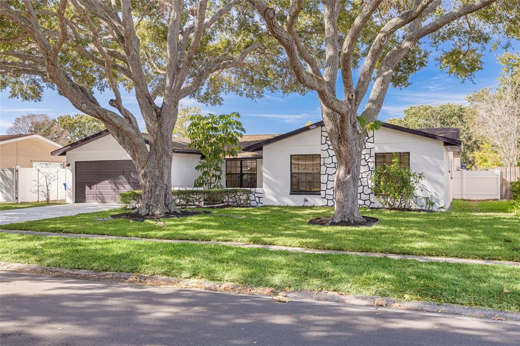 2034 58th Way North Clearwater, FL 33760 - Photo 2 of 35 a white house in a big yard with large trees