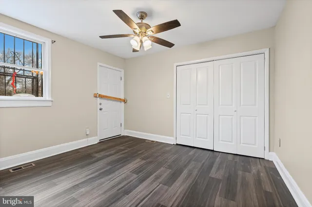 a view of an empty room with wooden floor and a ceiling fan