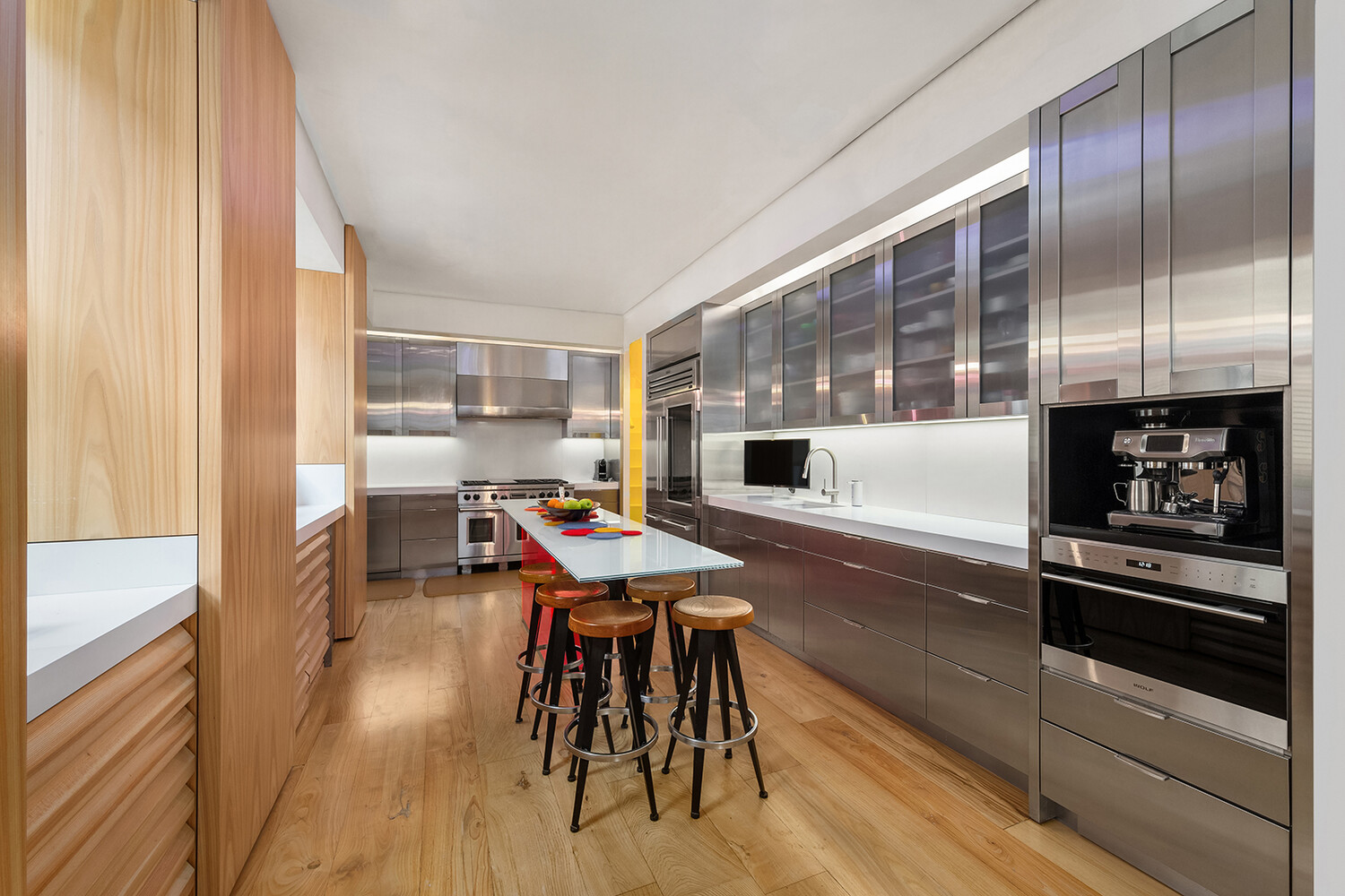 812 Park Avenue, Unit PHA Manhattan, NY 10021 - Photo 6 of 14 a kitchen with stainless steel appliances kitchen island granite countertop a stove a refrigerator a dining table and chairs with wooden floor