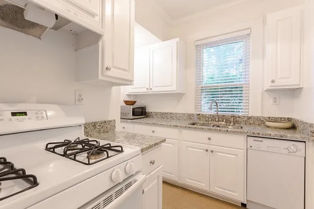 a kitchen with granite countertop white cabinets and white appliances