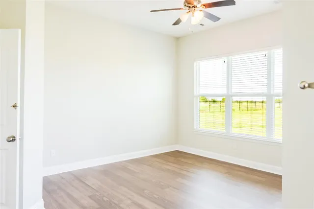 an empty room with a window and a ceiling fan