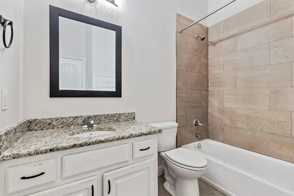 a bathroom with a granite countertop toilet sink and mirror
