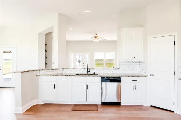 a kitchen with stainless steel appliances granite countertop a sink and cabinets with wooden floor
