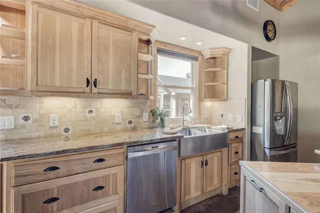 a kitchen with stainless steel appliances granite countertop a sink and a refrigerator