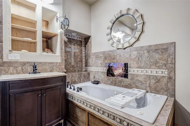 a bathroom with a granite countertop bathtub a sink and a mirror
