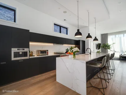 a kitchen with stainless steel appliances granite countertop a refrigerator a stove a sink dishwasher and a dining table with the view of kitchen