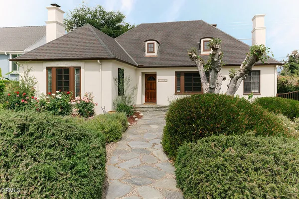 a house with a flower garden and potted plants