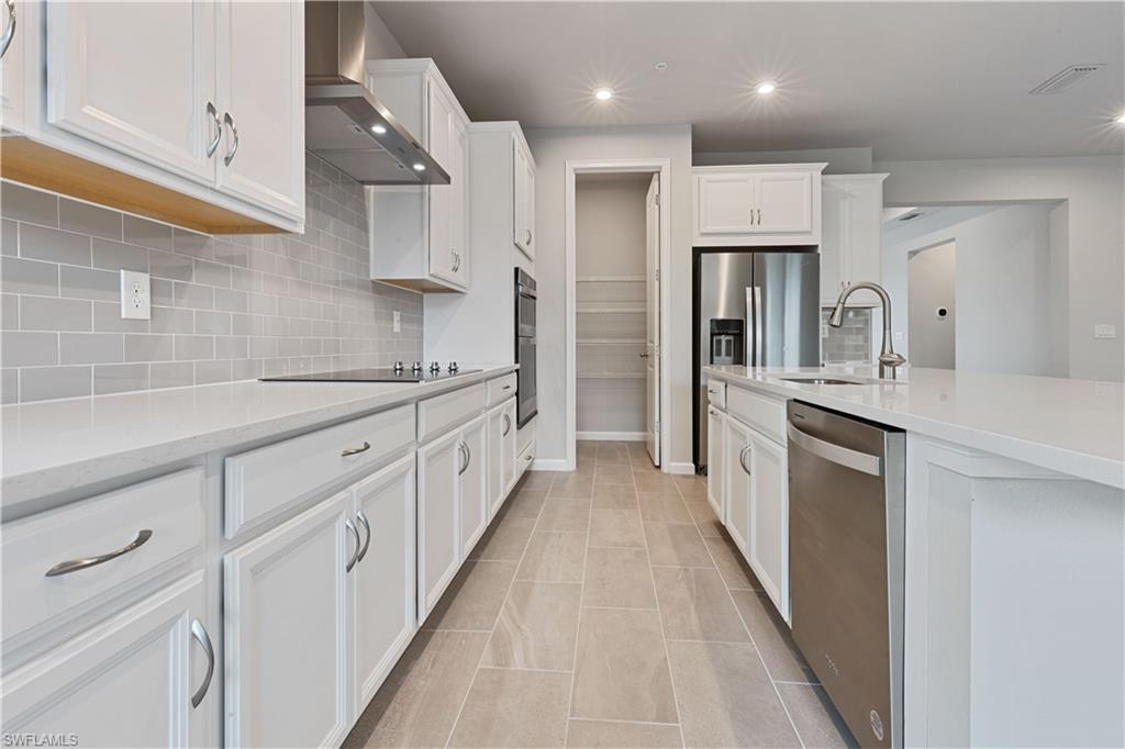 4670 Arboretum Circle, Unit 203 Naples, FL 34112 - Photo 14 of 33 a large kitchen with stainless steel appliances lots of counter space and wooden floor