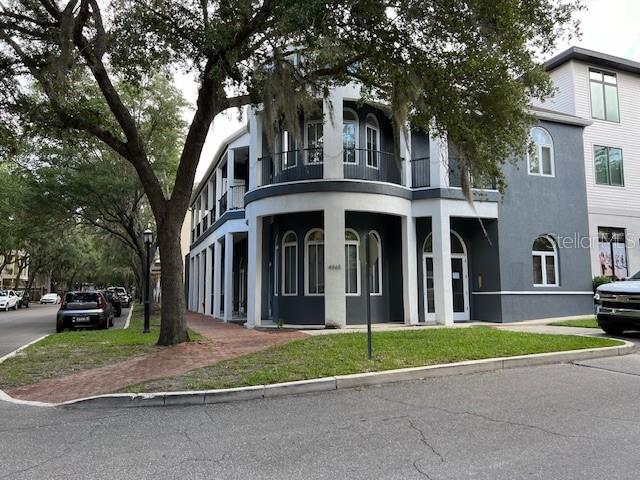 a view of a brick house with a yard and large trees