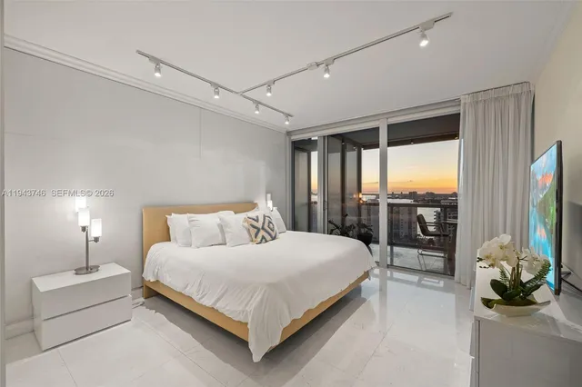 a bedroom with a bed flat screen tv and a large window