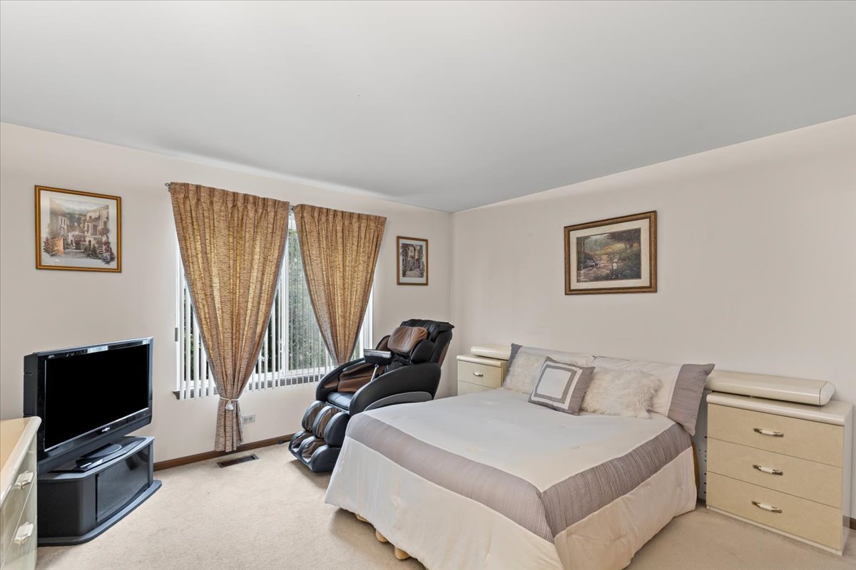 808 Violet Circle Naperville, IL 60540 - Photo 10 of 31 a bedroom with a bed a couch and a flat screen tv