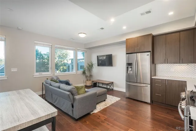 a living room with furniture wooden floor and a refrigerator