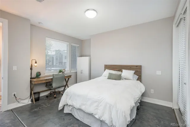 a bedroom with a bed table chair and a window