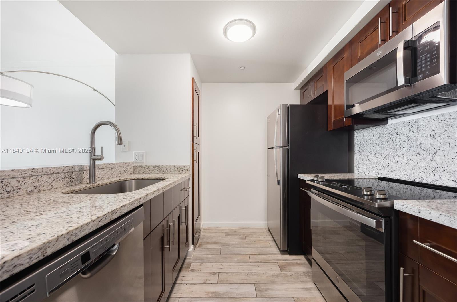 2889 McFarlane Road, Unit 1014 Coconut Grove, FL 33133 - Photo 6 of 15 a kitchen with granite countertop a sink stove and refrigerator