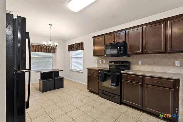 a kitchen with a refrigerator and a stove top oven