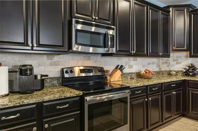 a kitchen with granite countertop a sink dishwasher a dining table and chairs with wooden floor