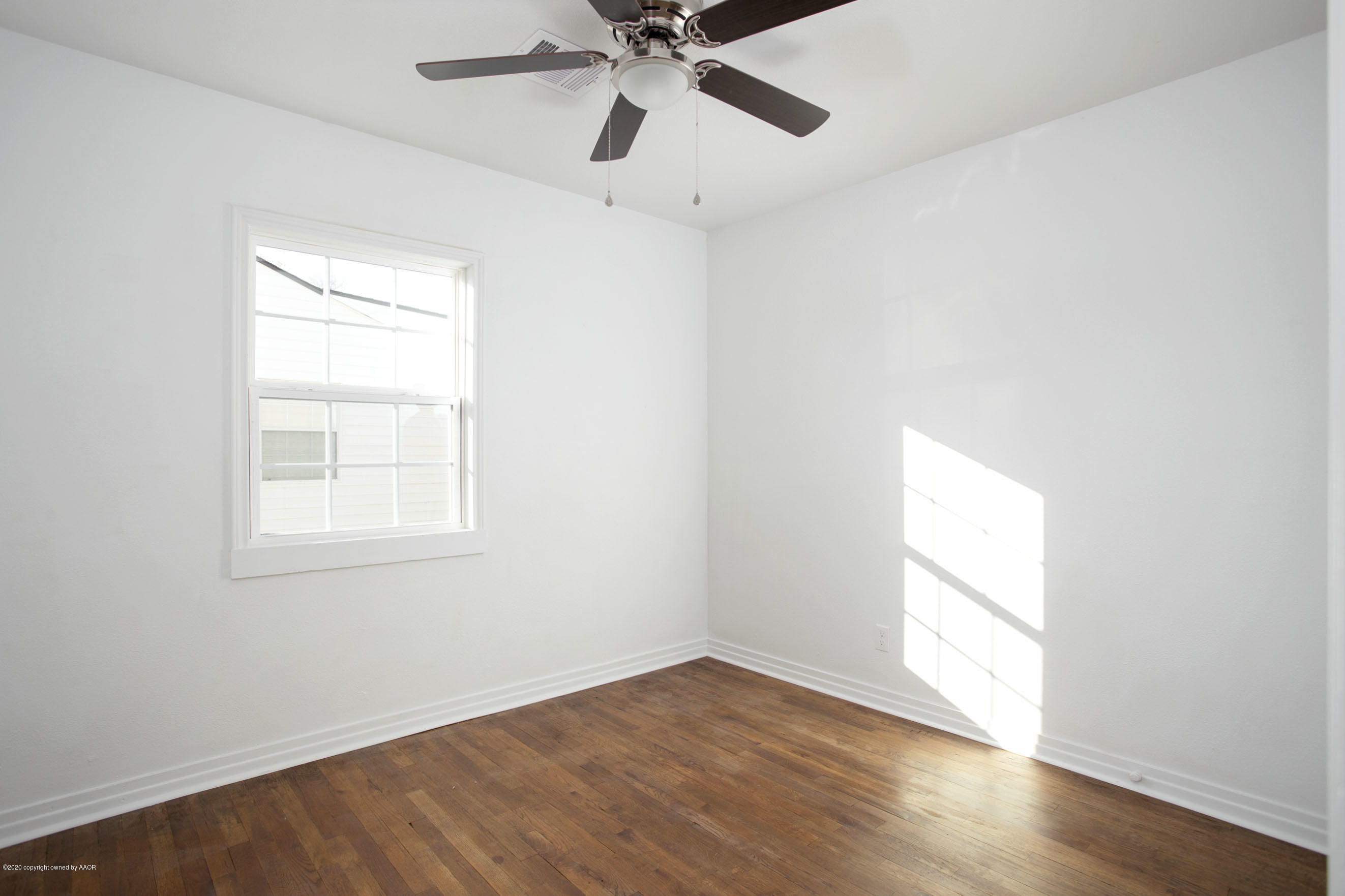 4408 South Travis Street Amarillo, TX 79110 - Photo 12 of 25 an empty room with wooden floor fan and windows