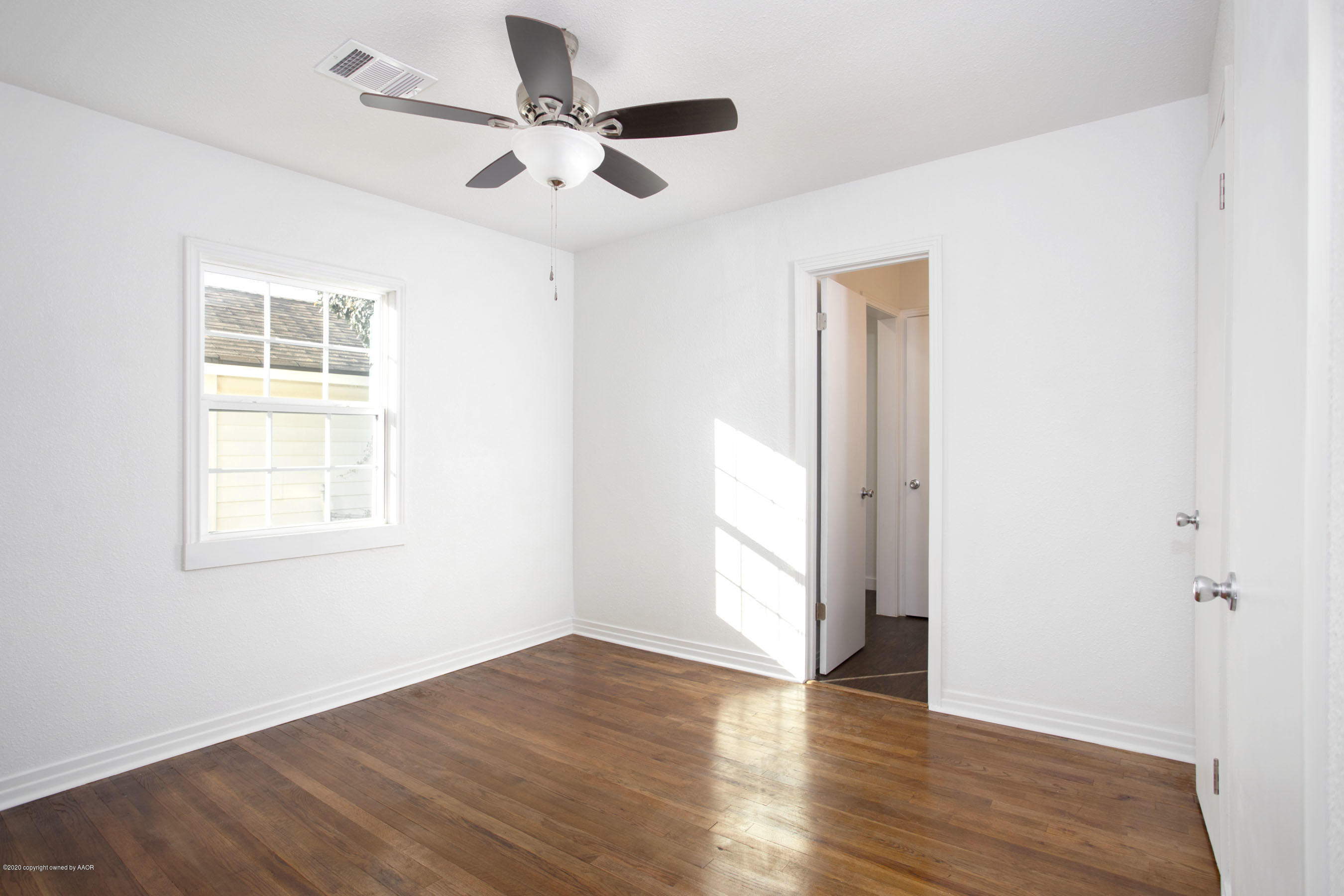 4408 South Travis Street Amarillo, TX 79110 - Photo 14 of 25 an empty room with wooden floor chandelier fan and windows