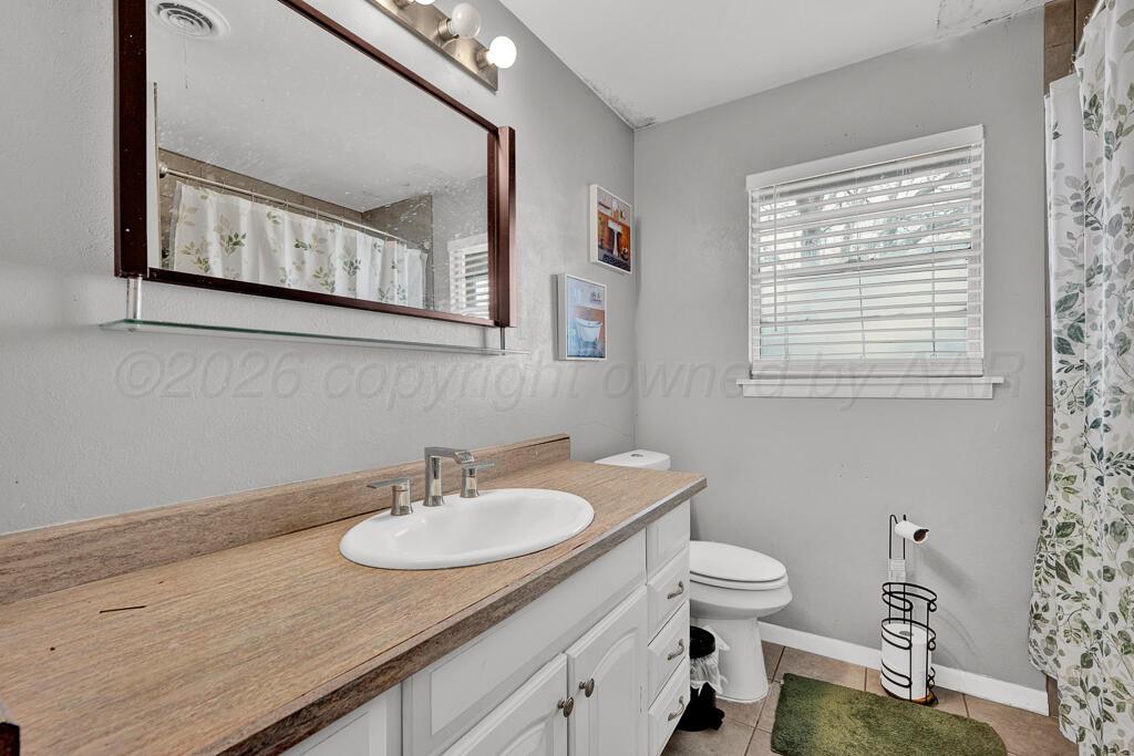 4613 South Bryan Street Amarillo, TX 79110 - Photo 10 of 16 a bathroom with a granite countertop sink a toilet and a mirror