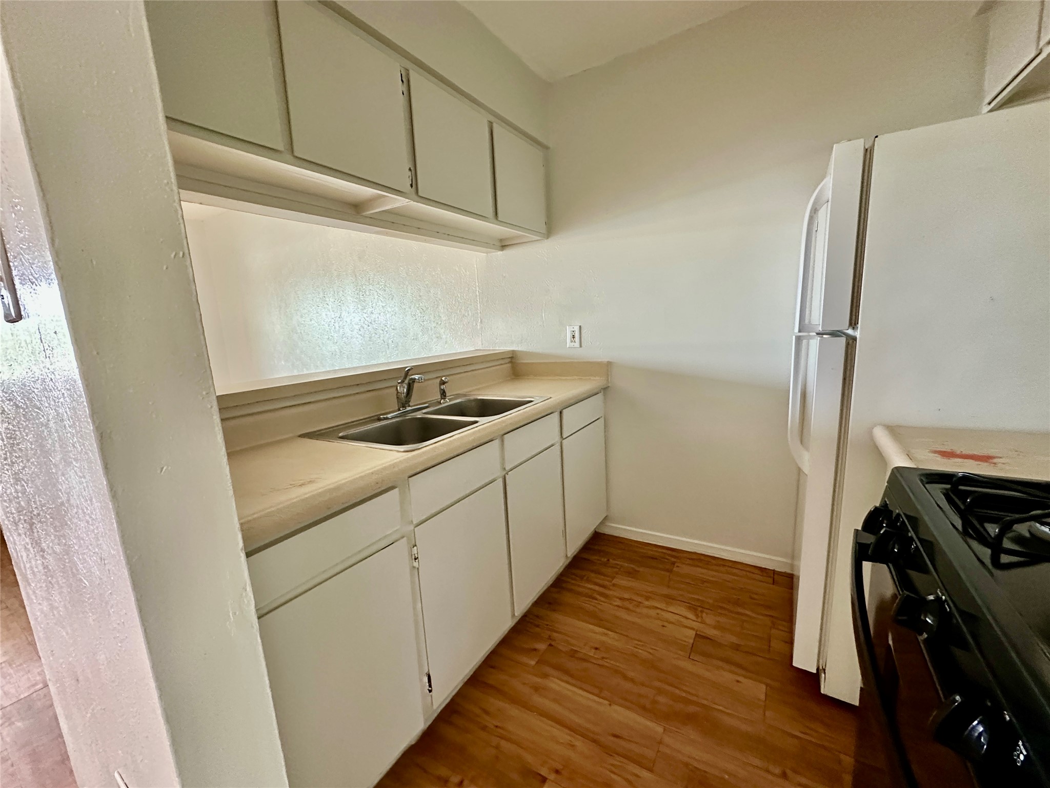 10810 Newmont Road, Unit 7 Austin, TX 78758 - Photo 3 of 13 The kitchen features white cabinetry, a double basin sink, and a white refrigerator