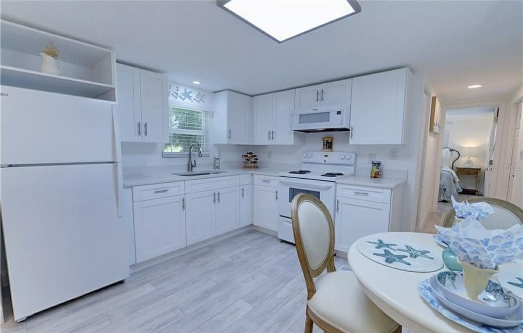 8164 East Turner Camp Road Inverness, FL 34453 - Photo 12 of 39 a kitchen with stainless steel appliances granite countertop a refrigerator a sink dishwasher a stove a dining table and chairs with wooden floor