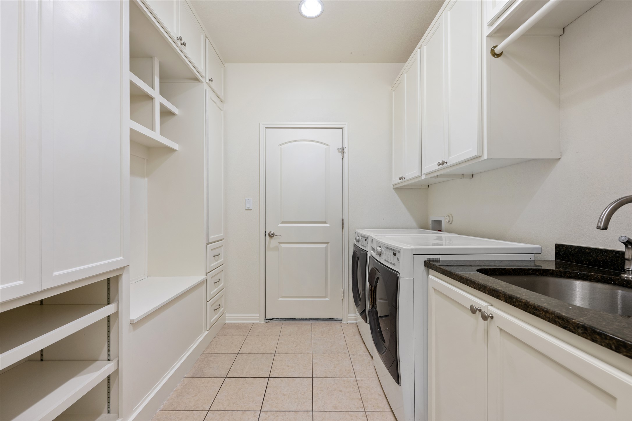 15205 Spillman Ranch Loop Austin, TX 78738 - Photo 26 of 40 Functional utility room featuring integrated cabinetry, a practical sink, and organized laundry facilities.